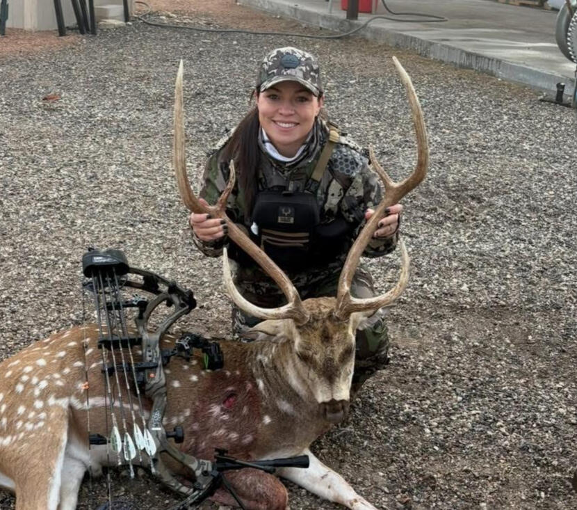 Bowhunting Camo: Built for the Field- A female bowhunter in full camo gear displays a harvested axis deer with her compound bow proof of performance from STX gear.